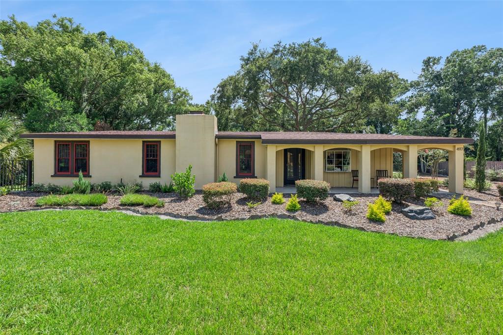 A paved patio features two lounge chairs, a dining set with an umbrella, and string lights — 497 VALENCIA STREET, SANFORD, FL
