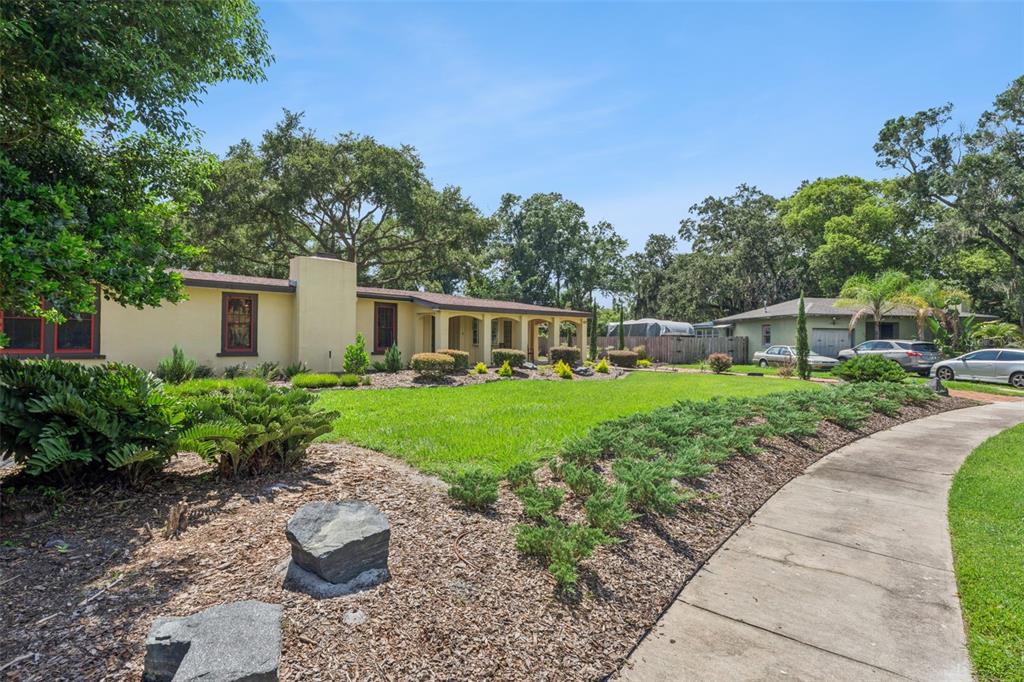 A single-story house with a paved patio and large tree at sunset — 497 VALENCIA STREET, SANFORD, FL