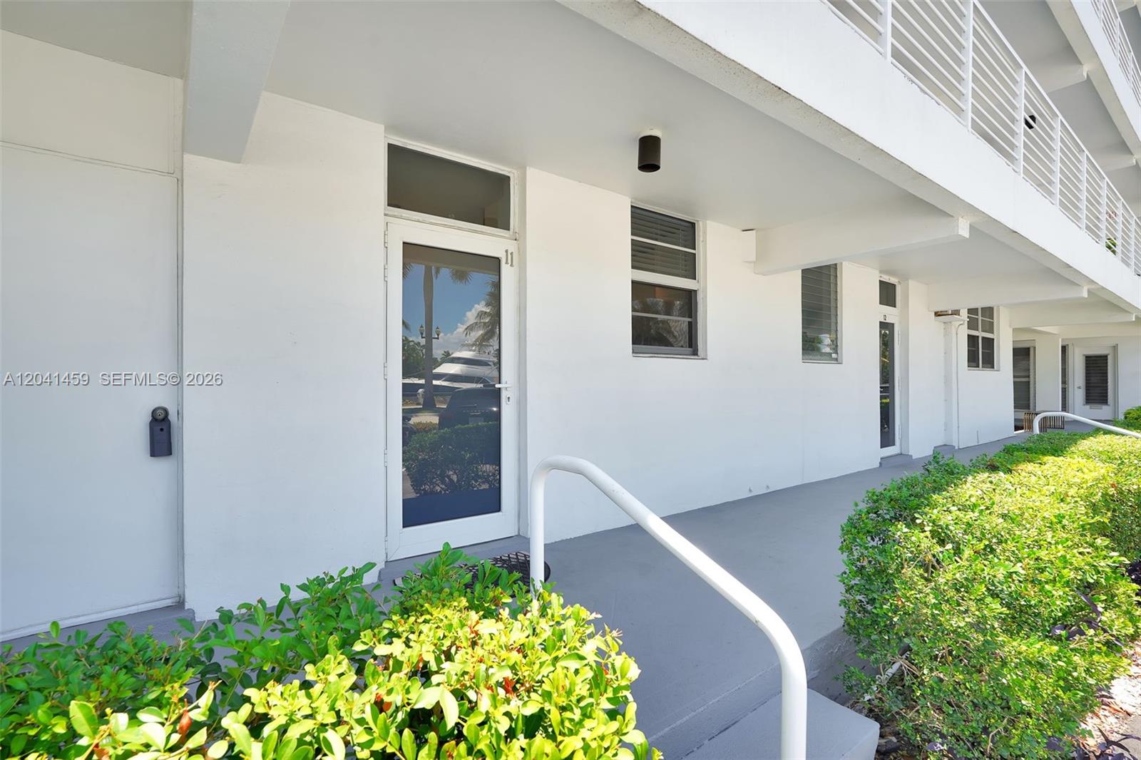 A ground-level exterior view shows a white building with several doors and a walkway — 1790 E Las Olas Blvd # 11, Fort Lauderdale FL 33301, FORT LAUDERDALE, FL