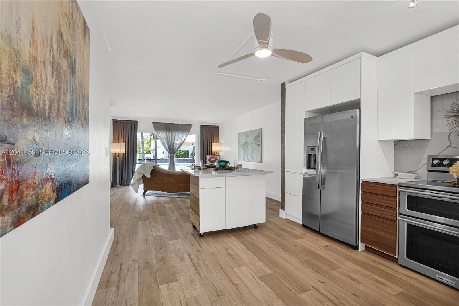 A modern kitchen with white cabinetry and a mobile island opens into a living area — 1790 E Las Olas Blvd # 11, Fort Lauderdale FL 33301, FORT LAUDERDALE, FL
