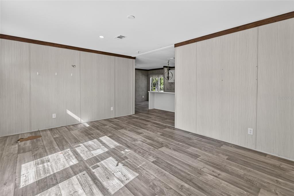 An interior view of a living area with light wood-paneled walls and gray wood flooring — 17538 EVELYN COURT, SPRING HILL, FL