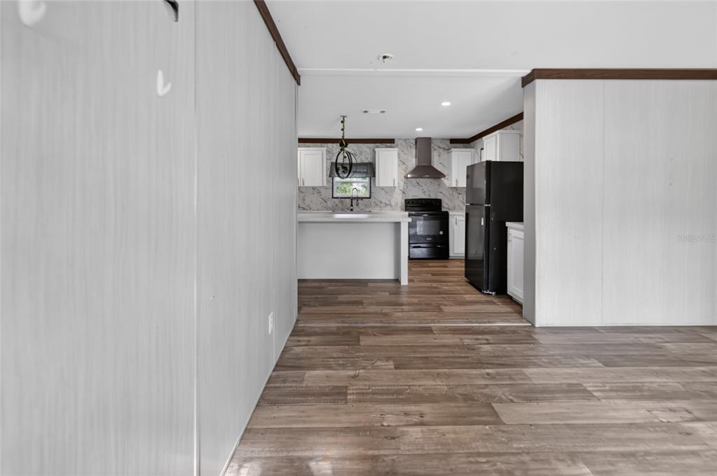 A view from a living area looking into a kitchen with wood-look flooring — 17538 EVELYN COURT, SPRING HILL, FL