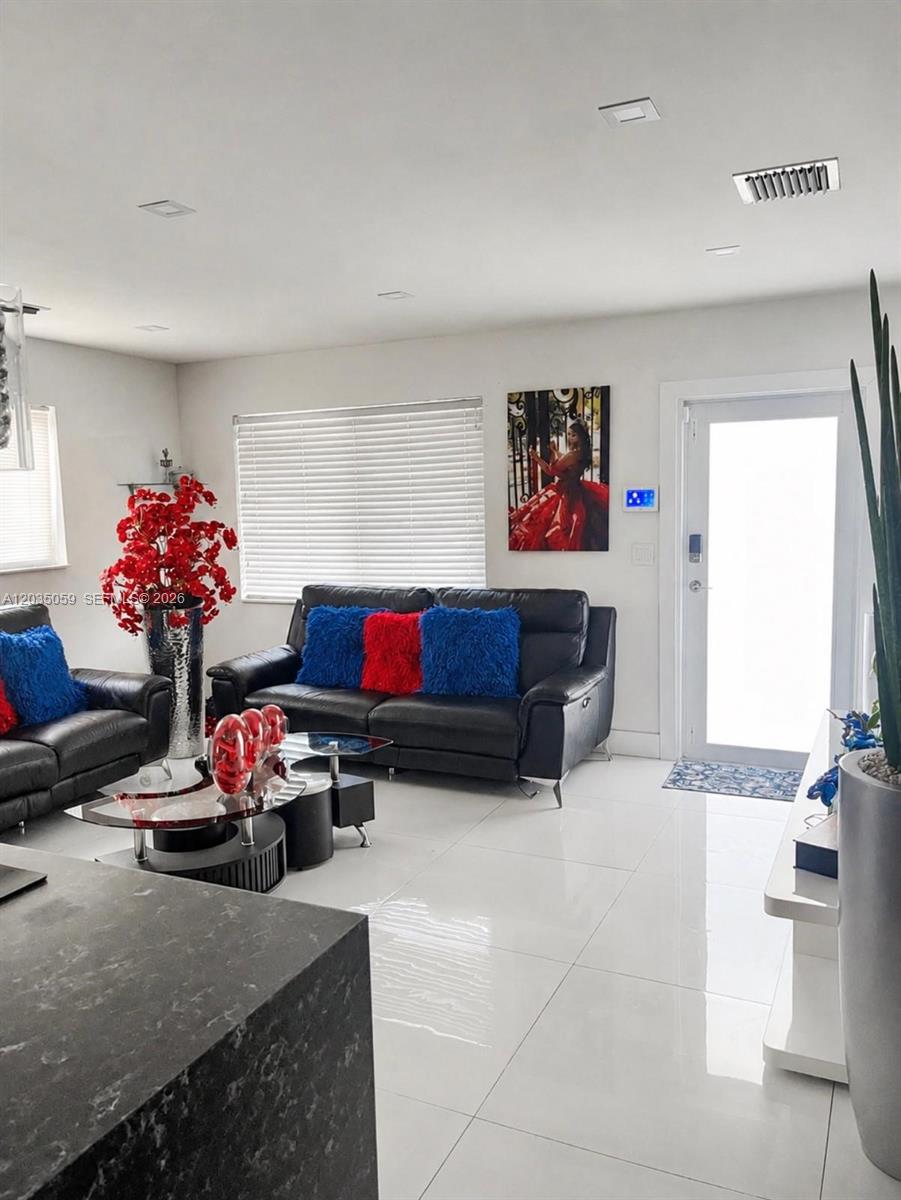 A living room features black leather sofas, red and blue pillows, and white tile flooring — 1220 N 71st Ter, Hollywood FL 33024, HOLLYWOOD, FL