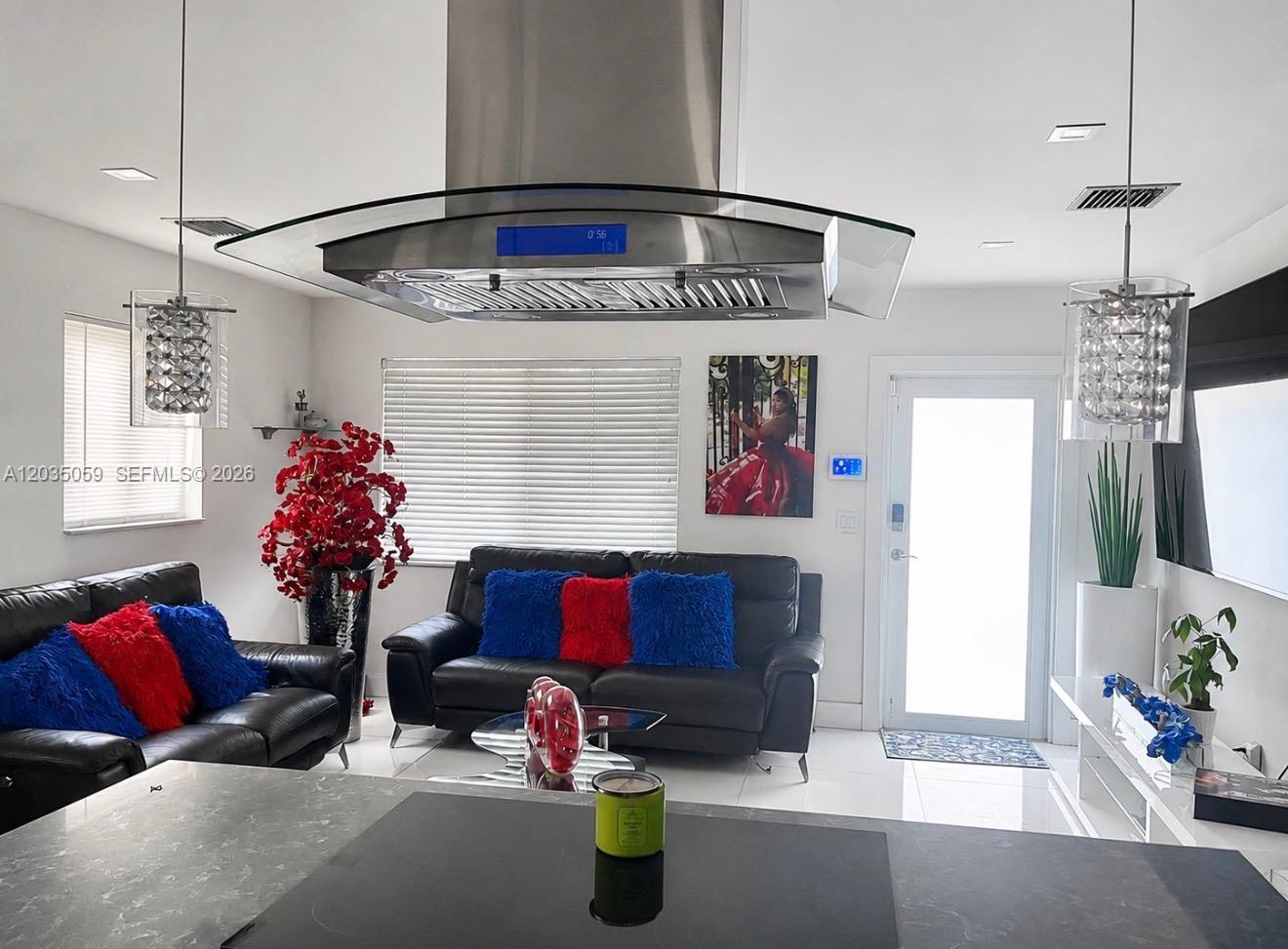 A modern living room features black leather sofas, a large range hood, and white tile flooring — 1220 N 71st Ter, Hollywood FL 33024, HOLLYWOOD, FL