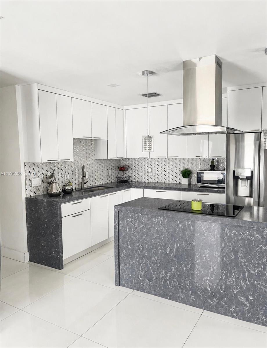 A modern kitchen features white cabinets, gray marble-patterned countertops, and a stainless steel range hood — 1220 N 71st Ter, Hollywood FL 33024, HOLLYWOOD, FL