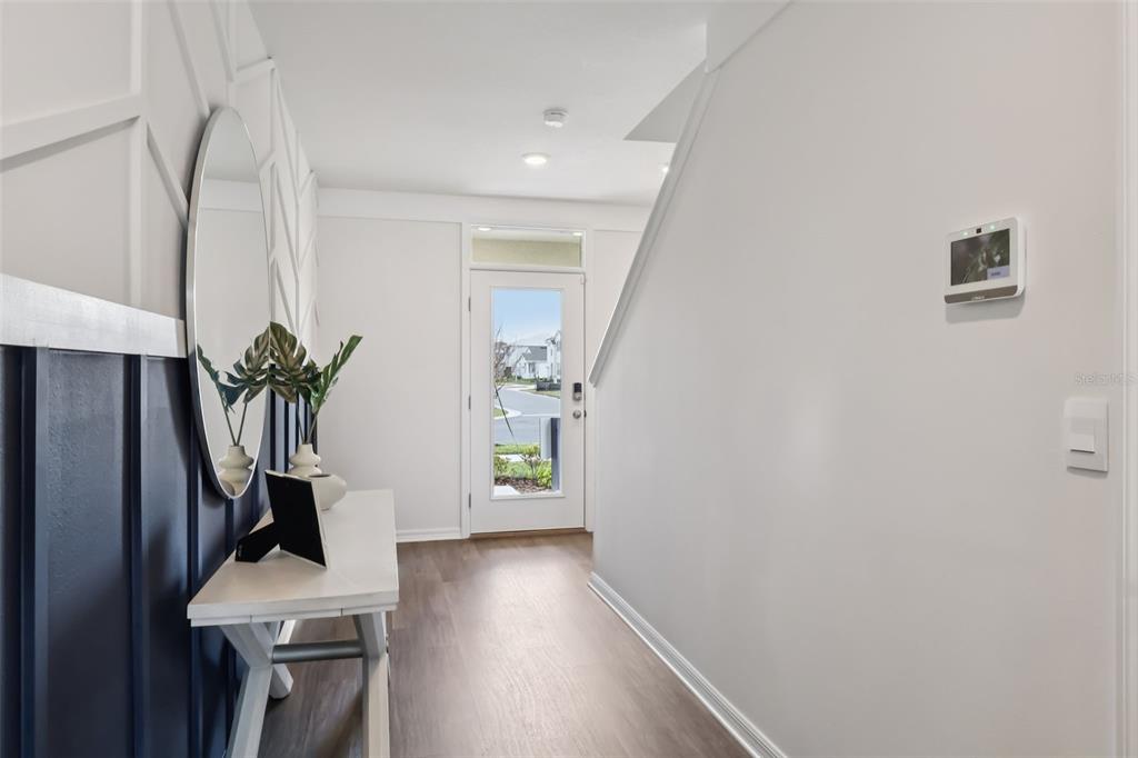 A bright entryway features a white console table, a round mirror, and dark blue wainscoting — 5168 PENELOPE TRAIL, LAKELAND, FL