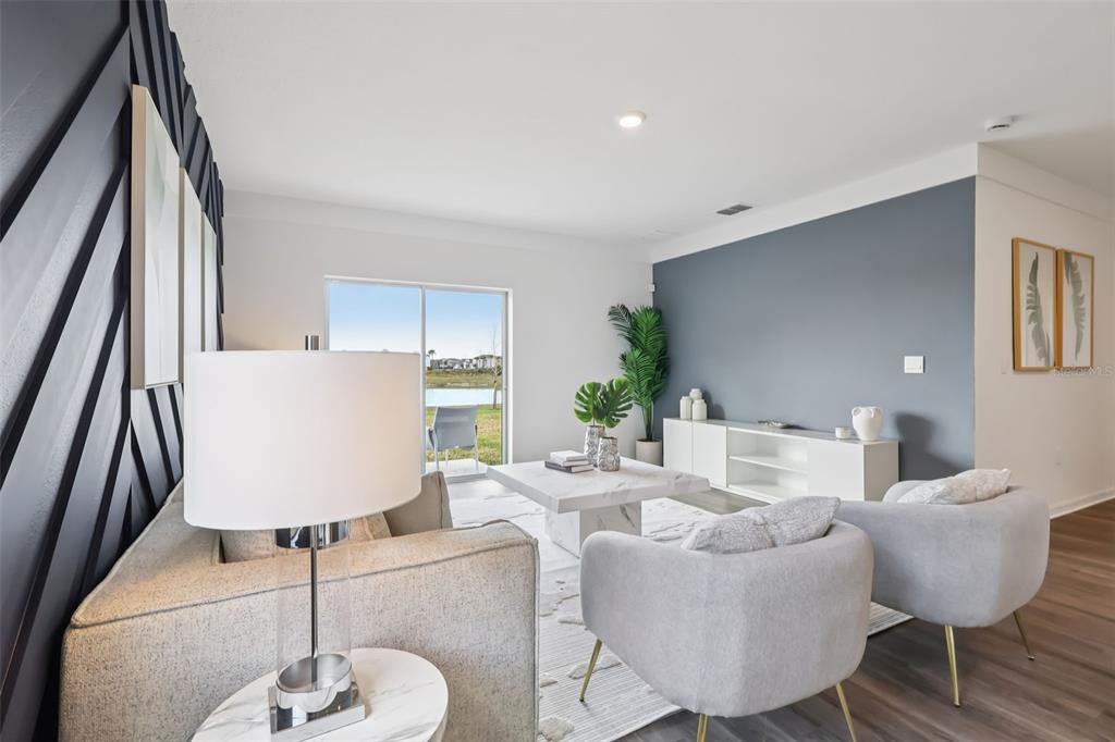 A living room features a dark accent wall, light furniture, and a view of a lake — 5168 PENELOPE TRAIL, LAKELAND, FL