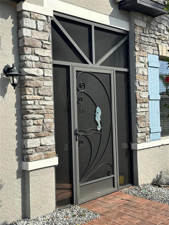 A front entrance features a decorative metal screen door with a seahorse accent and stone siding — 2137 APIAN WAY, PORT CHARLOTTE, FL