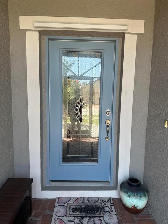 A blue front door with a decorative glass insert sits within a white-trimmed entryway — 2137 APIAN WAY, PORT CHARLOTTE, FL
