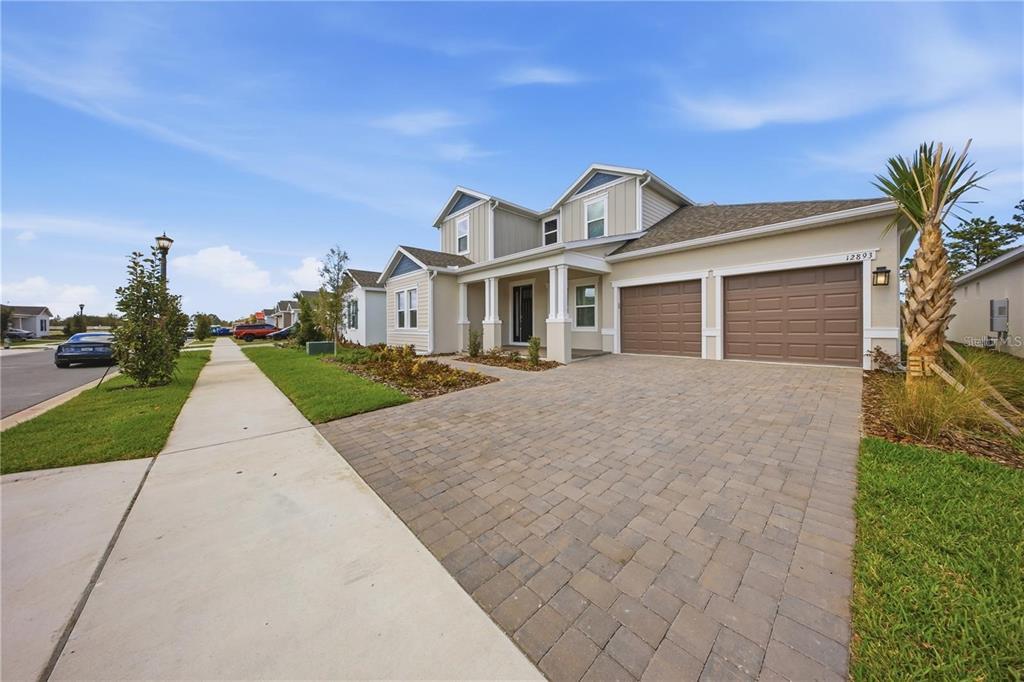 A two-story suburban house with a paved driveway, two-car garage, and light-colored siding — 12893 HARVEST RAIN AVENUE, WINTER GARDEN, FL