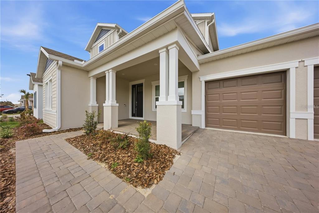 A beige house exterior features a covered entryway with white columns and a paved driveway — 12893 HARVEST RAIN AVENUE, WINTER GARDEN, FL