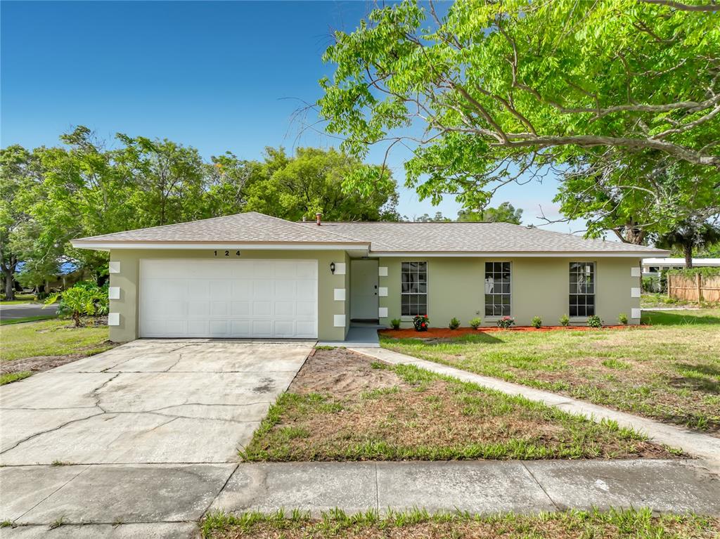 A single-story house with a light green exterior, white garage door, and a concrete driveway — 124 HOLLYHOCK DRIVE, ALTAMONTE SPRINGS, FL