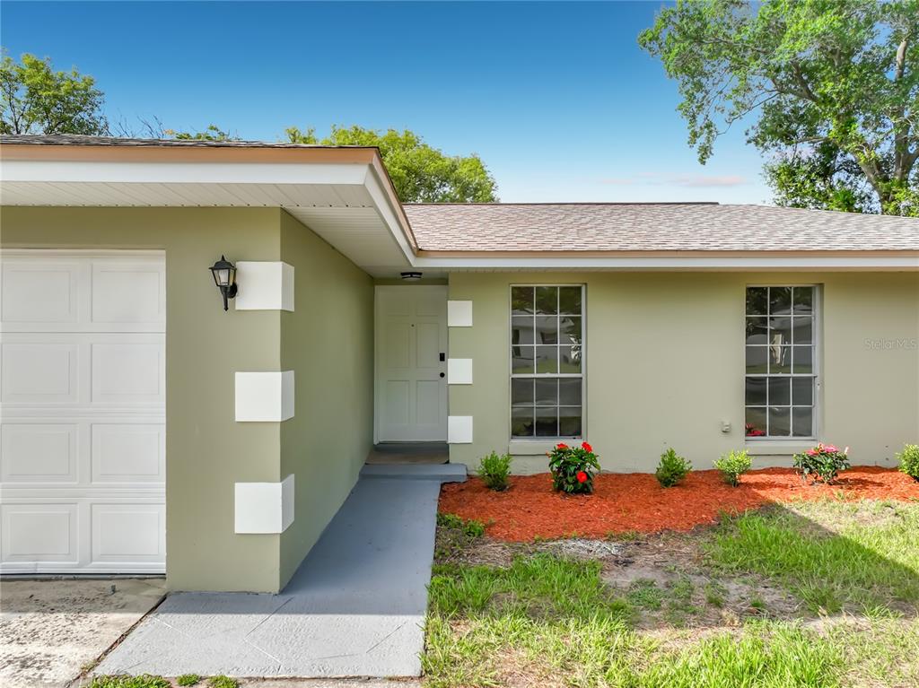 A light green house exterior features a white garage door, front door, and two windows — 124 HOLLYHOCK DRIVE, ALTAMONTE SPRINGS, FL