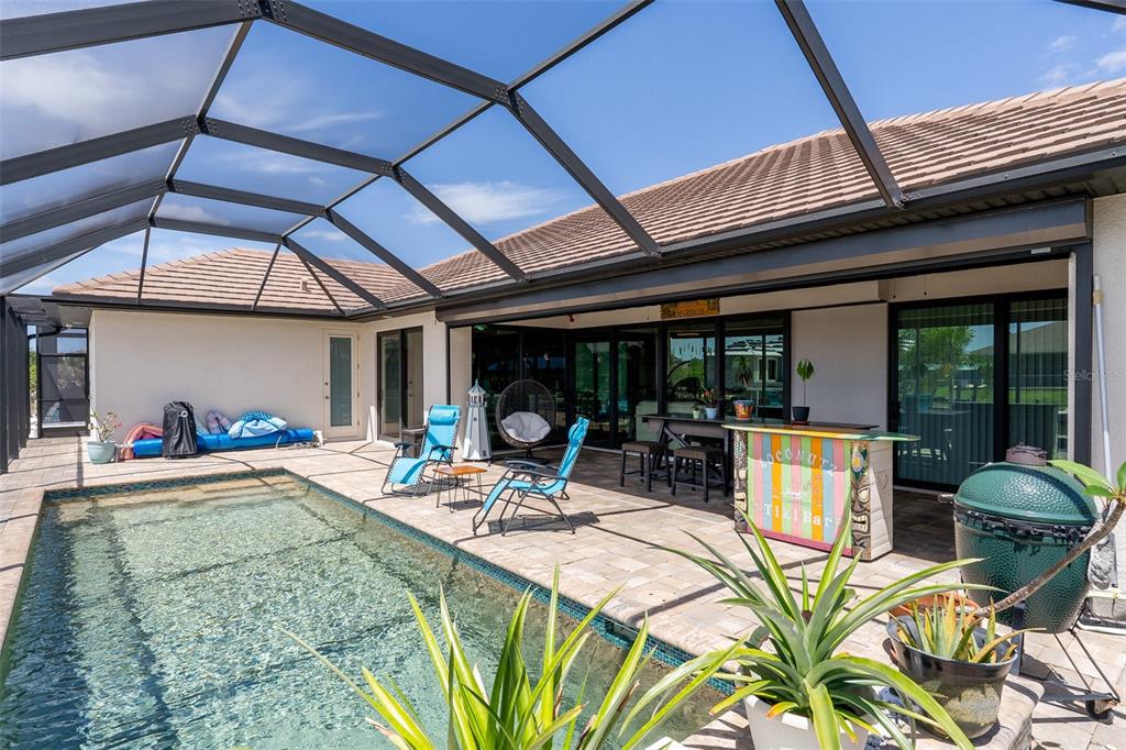 A screened-in patio features a swimming pool, a tiki bar, and outdoor seating — 15252 CHINOOK WAY, PORT CHARLOTTE, FL