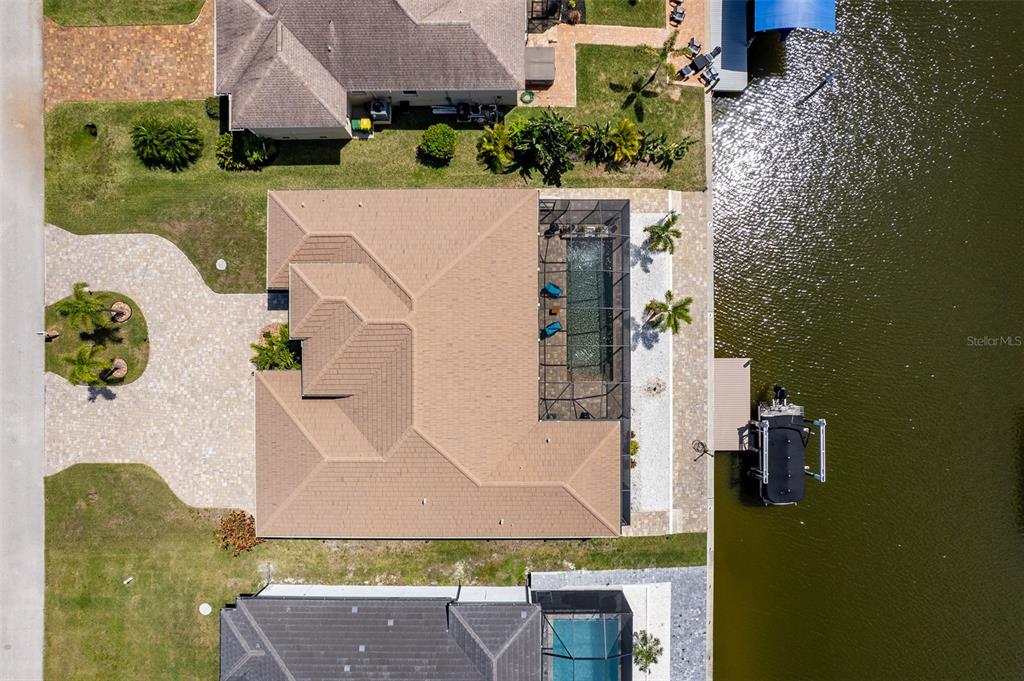 An aerial view shows a house with a tan roof, pool cage, and private dock — 15252 CHINOOK WAY, PORT CHARLOTTE, FL