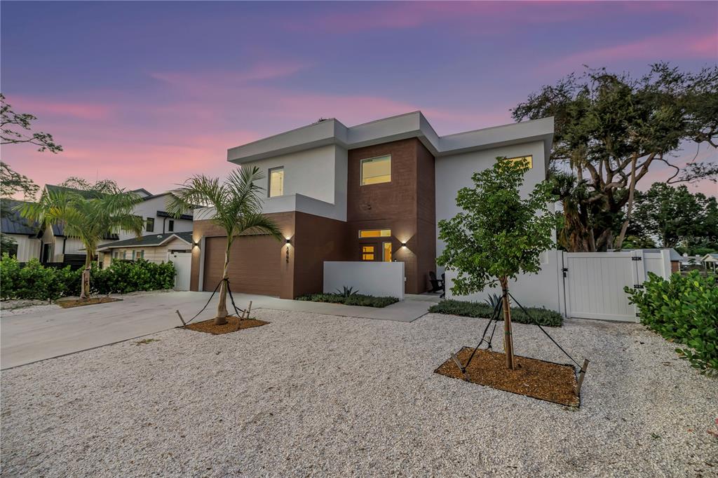 A modern two-story house with a brown and white exterior sits behind a gravel yard — 2065 GOLDENROD STREET, SARASOTA, FL