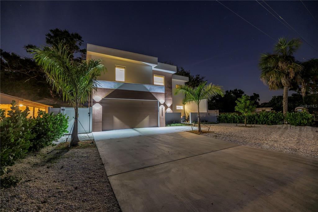 A modern two-story house with a concrete driveway and palm trees at night — 2065 GOLDENROD STREET, SARASOTA, FL