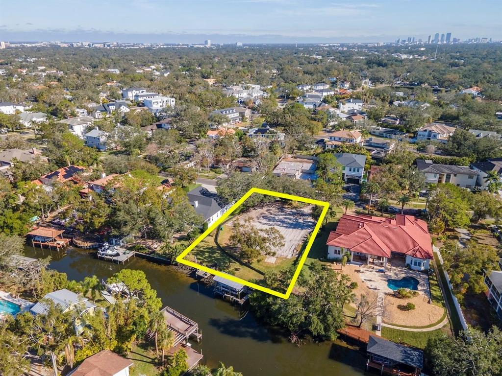 An aerial view shows a vacant waterfront lot outlined in yellow next to a large house — 2609 N DUNDEE STREET, TAMPA, FL