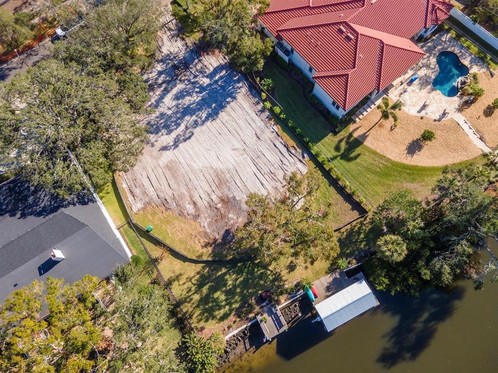 An aerial view shows a vacant waterfront lot situated between two existing residential properties — 2609 N DUNDEE STREET, TAMPA, FL