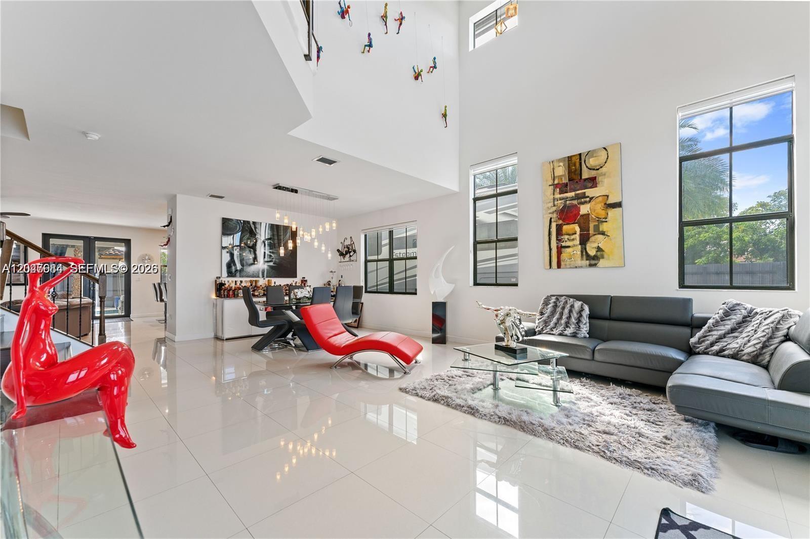 A modern living and dining room features high ceilings, white tile floors, and contemporary furniture — 14856 SW 27th Ter, Miami FL 33185, MIAMI, FL