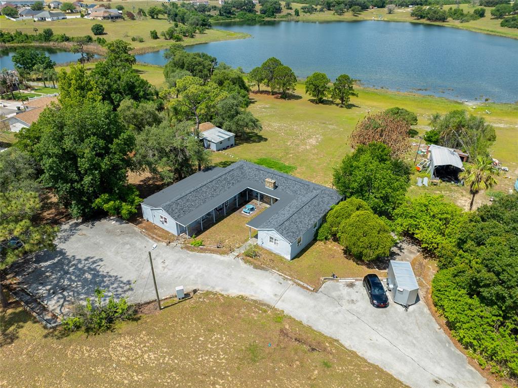 An aerial view shows a U-shaped house with a dark roof near a lake — 1210 STATE 17 ROAD S, DUNDEE, FL