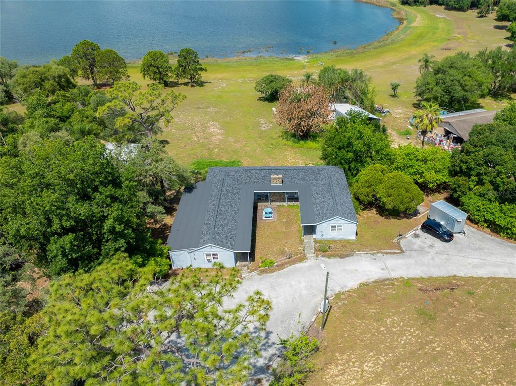 An aerial view shows a U-shaped house with a dark roof situated near a lake — 1210 STATE 17 ROAD S, DUNDEE, FL