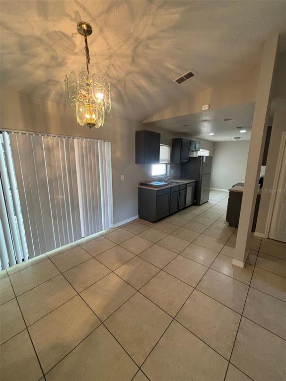 A kitchen with dark cabinets and tile flooring sits adjacent to a dining area — 661 N DELMONTE COURT, KISSIMMEE, FL