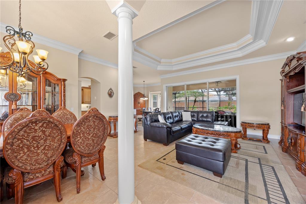 An open-concept living and dining area features a white column, tile floors, and tray ceilings — 1276 RAMROD STREET, NORTH PORT, FL