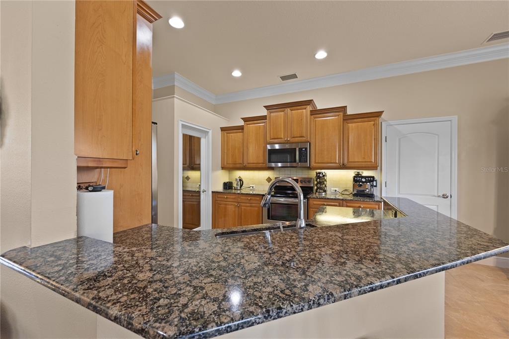A kitchen features wood cabinets, granite countertops, and stainless steel appliances — 1276 RAMROD STREET, NORTH PORT, FL