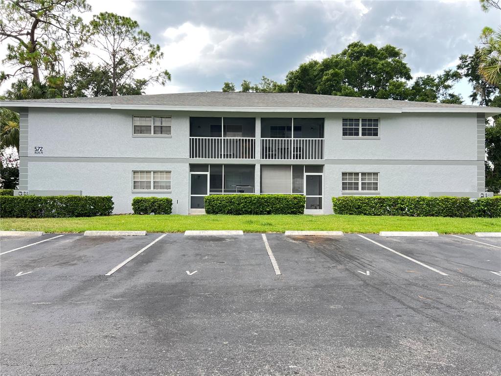 A two-story apartment building with a gray stucco exterior and a parking lot in front — 572 SE FAIRWAYS LANE UNIT N204, OCALA, FL