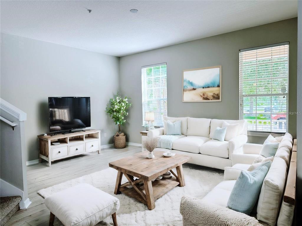A living room features a white sofa, a wooden coffee table, and a television console — 10341 LAKE DISTRICT LANE UNIT 55B, ORLANDO, FL