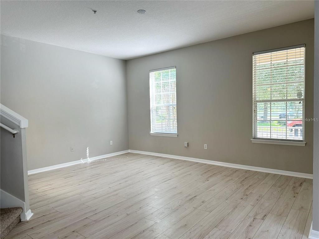 An empty room with light wood-look flooring, gray walls, and two windows with blinds — 10341 LAKE DISTRICT LANE UNIT 55B, ORLANDO, FL