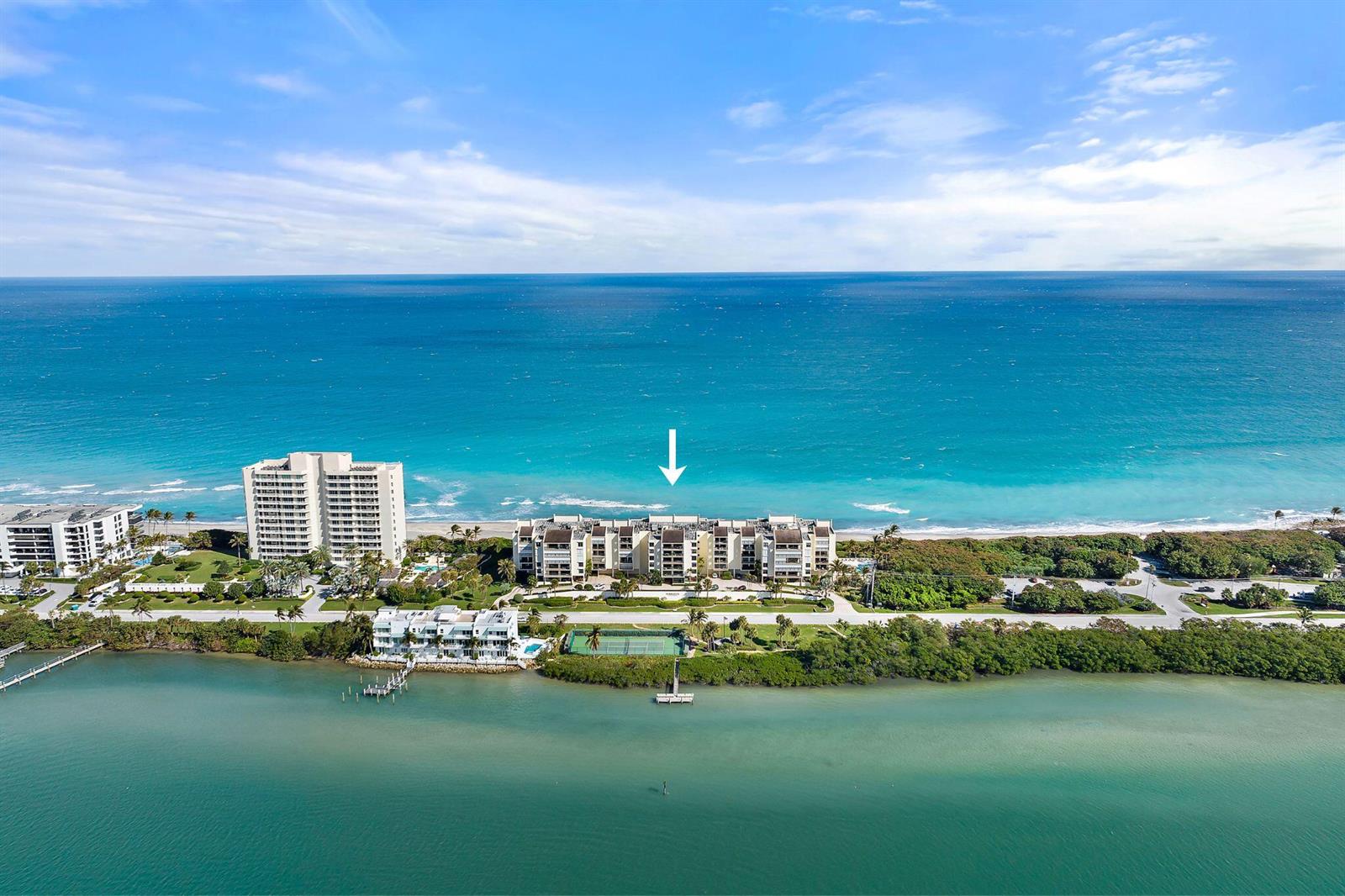 An aerial view shows a beachfront condominium complex situated between the ocean and a bay — 19670 Beach Road # C513, Jupiter FL 33469, JUPITER, FL