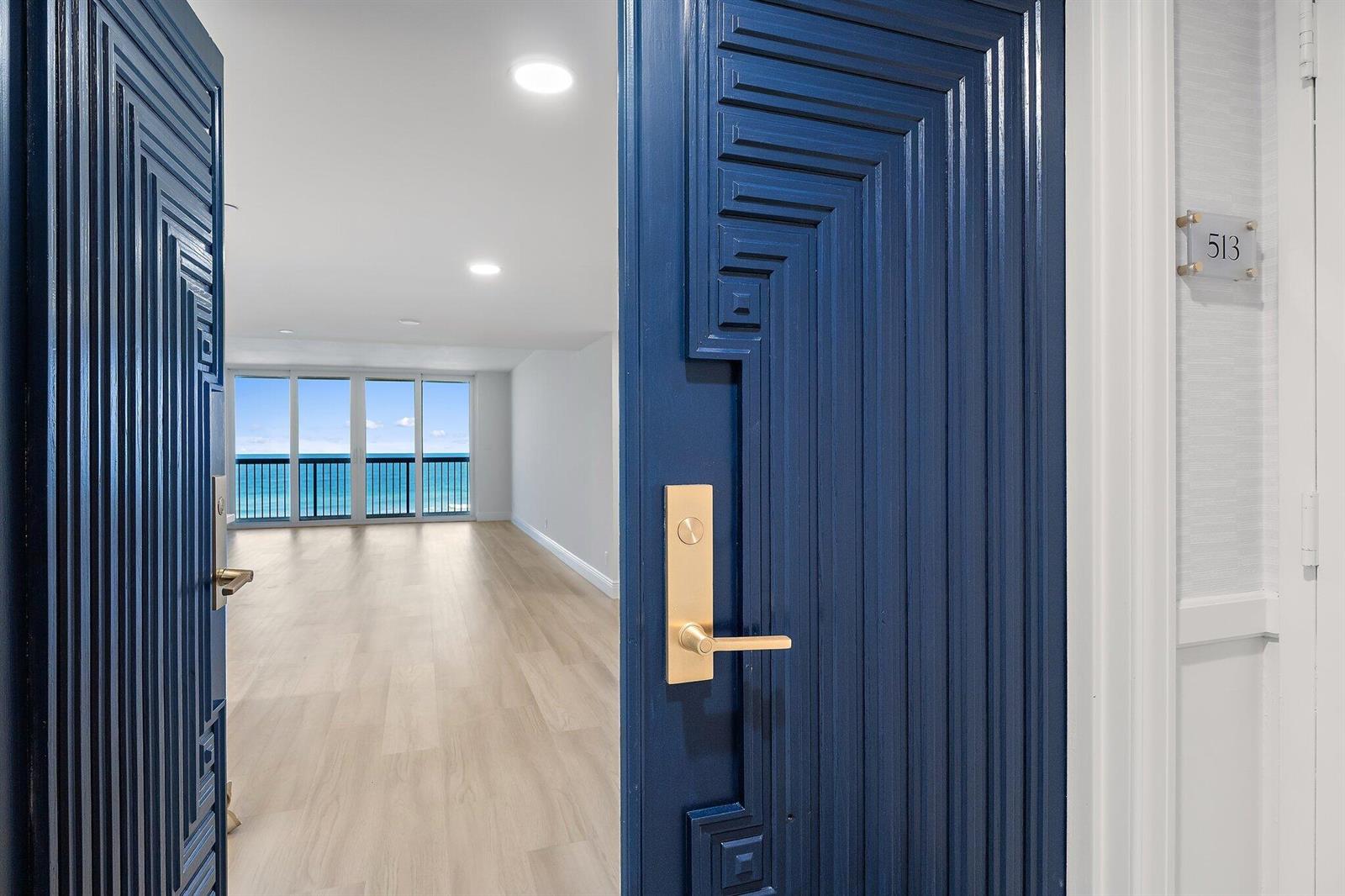A blue door with geometric molding opens into a bright, empty room with ocean views — 19670 Beach Road # C513, Jupiter FL 33469, JUPITER, FL