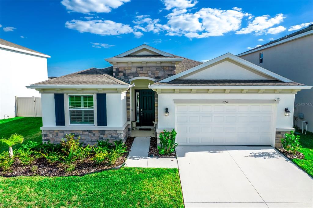 A single-story house with a stone facade, white stucco walls, and a two-car garage — 176 BRIGHT IBIS AVENUE, APOLLO BEACH, FL