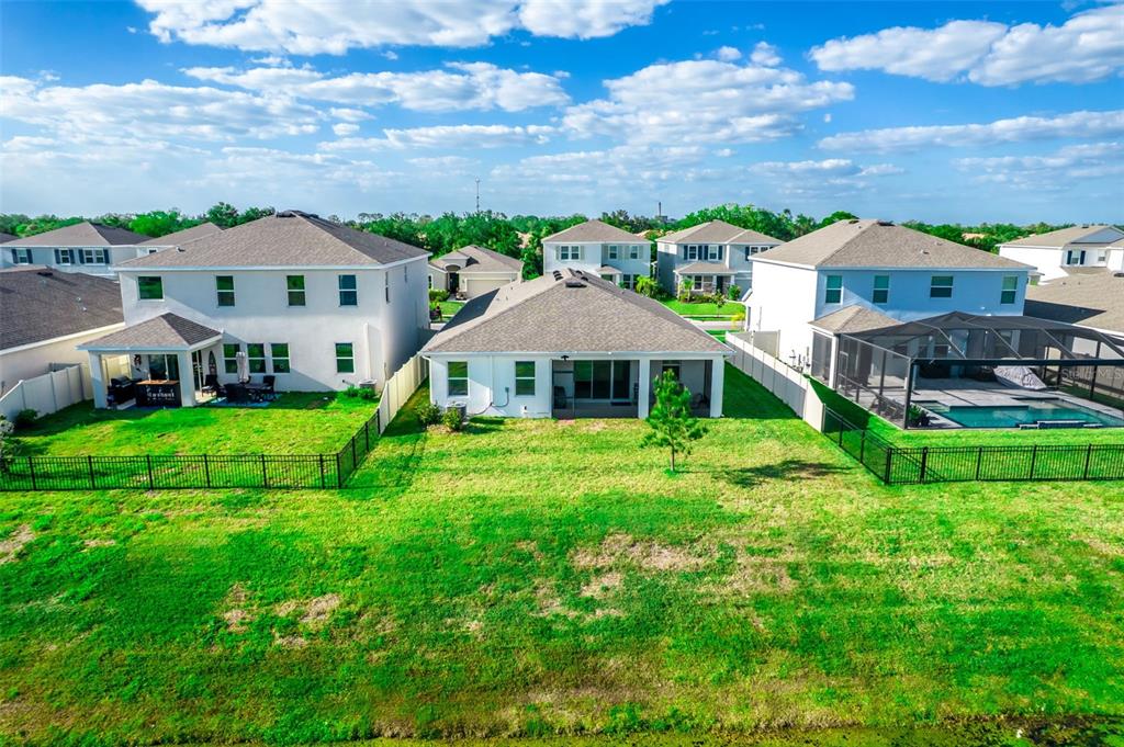 An aerial view shows the backyards of several suburban houses with fences and a pool — 176 BRIGHT IBIS AVENUE, APOLLO BEACH, FL