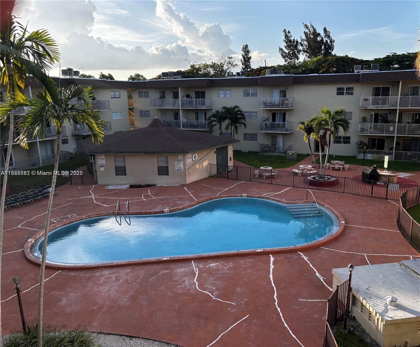 An outdoor swimming pool is surrounded by a patio with decorative cracks and apartment buildings — 7505 SW 82nd St # 318, Miami FL 33143, MIAMI, FL