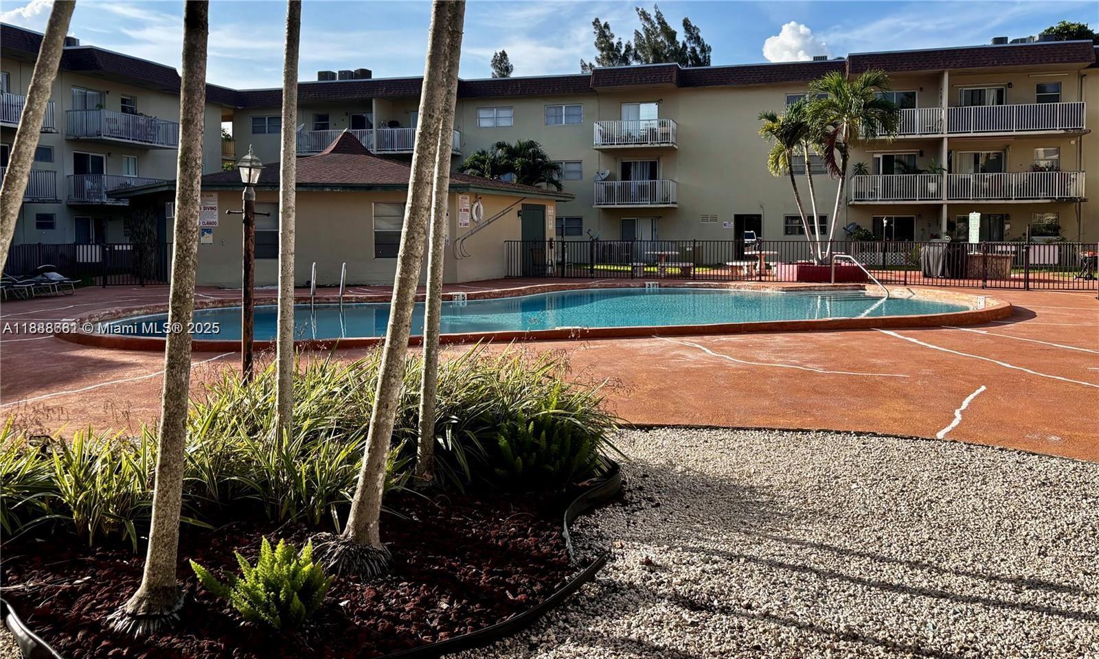 A swimming pool sits in front of a multi-story apartment building with balconies — 7505 SW 82nd St # 318, Miami FL 33143, MIAMI, FL