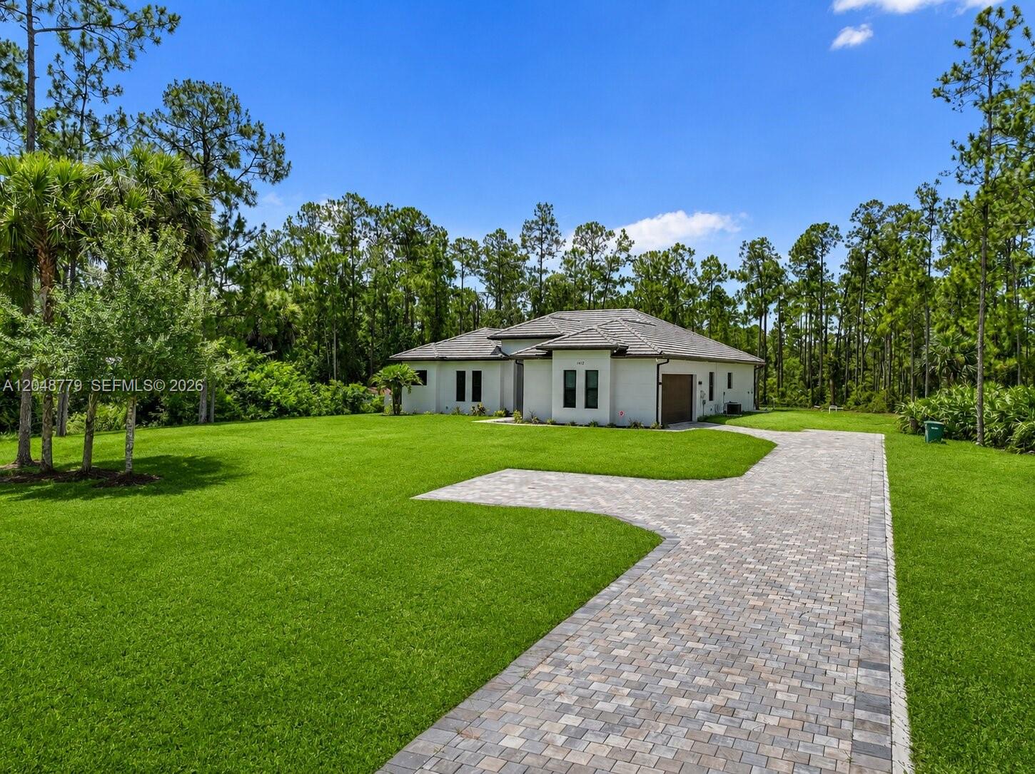 A single-story white house with a tiled roof and a paved driveway sits on grass — 1412 22nd Ave NE, Naples FL 34120, NAPLES, FL