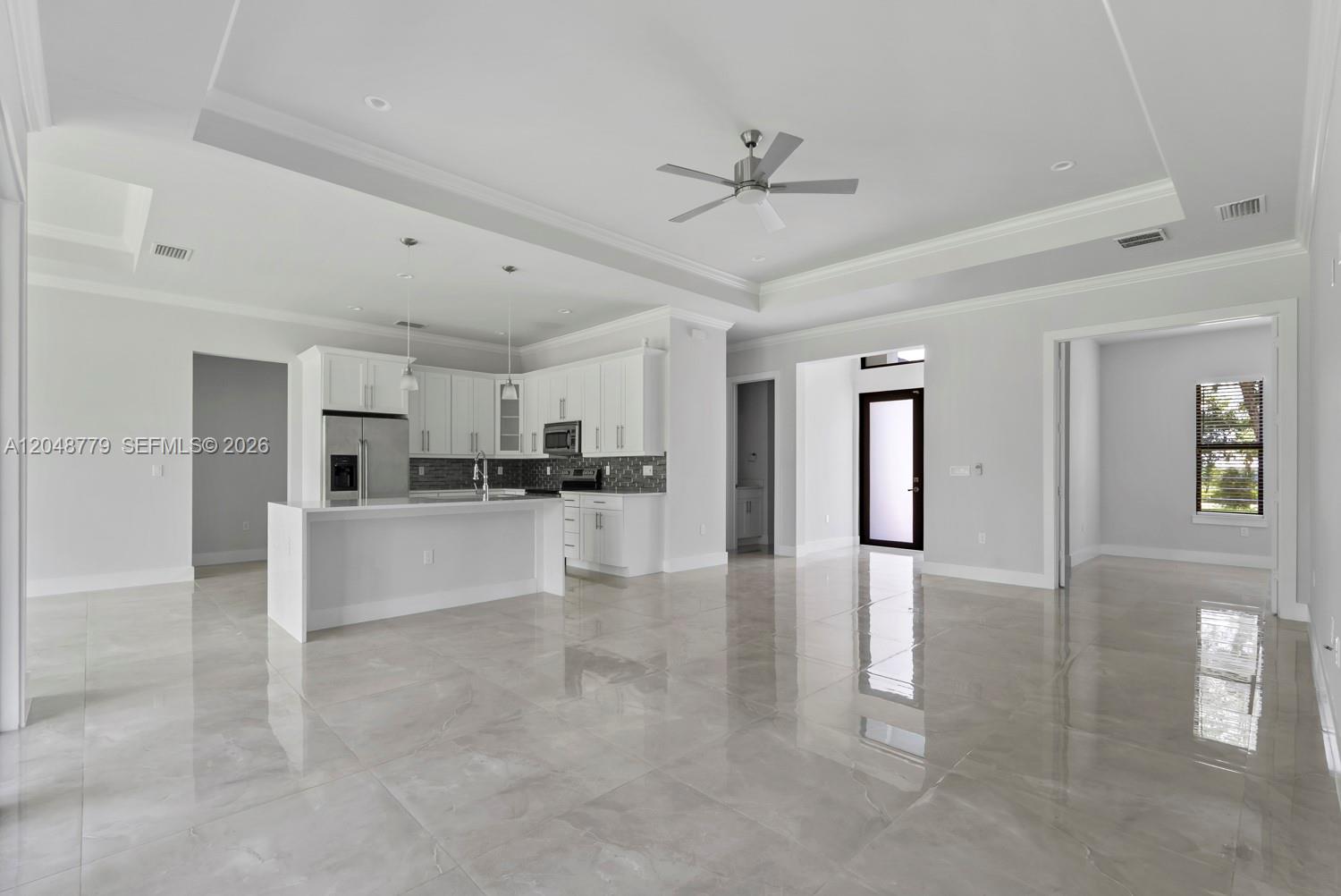 A bright, open-concept kitchen and living area features white cabinetry, a center island, and tile flooring — 1412 22nd Ave NE, Naples FL 34120, NAPLES, FL