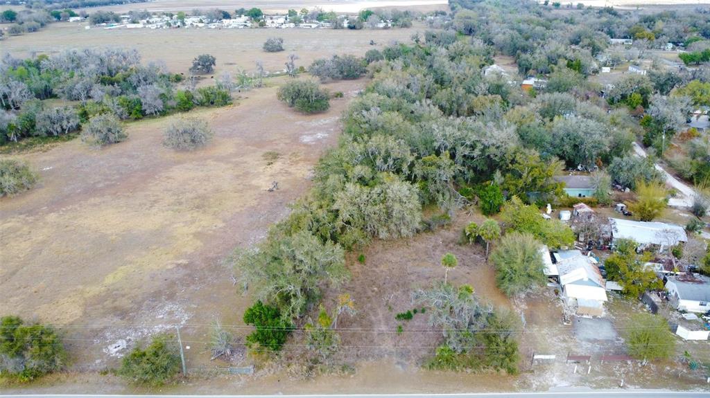 An aerial view shows a vacant lot with trees and brush next to residential houses — DURRANCE STREET SE, ARCADIA, FL