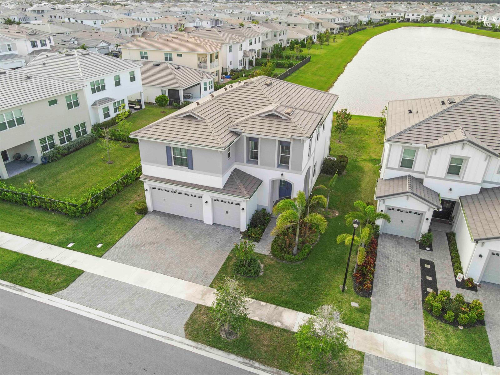 An aerial view shows a two-story suburban house with a gray tile roof and driveway — 5236 Liberty Lane, Westlake FL 33470, WESTLAKE, FL
