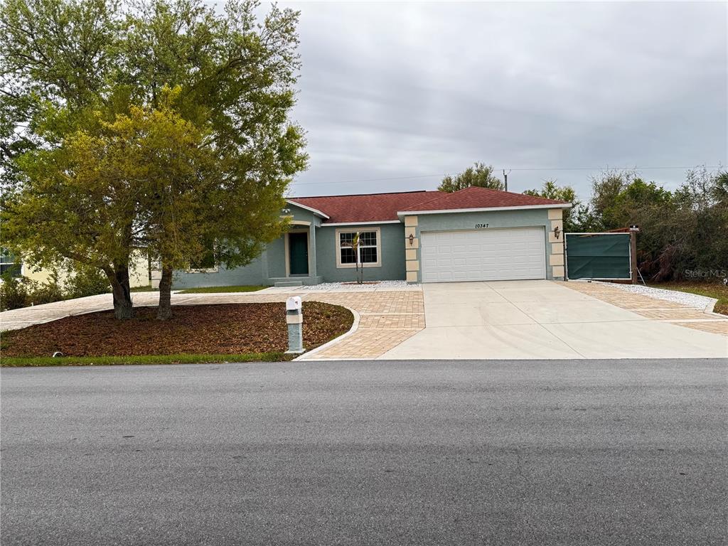 A single-story house with a teal exterior, red roof, and a paved driveway — 10347 GRAIL AVENUE, ENGLEWOOD, FL