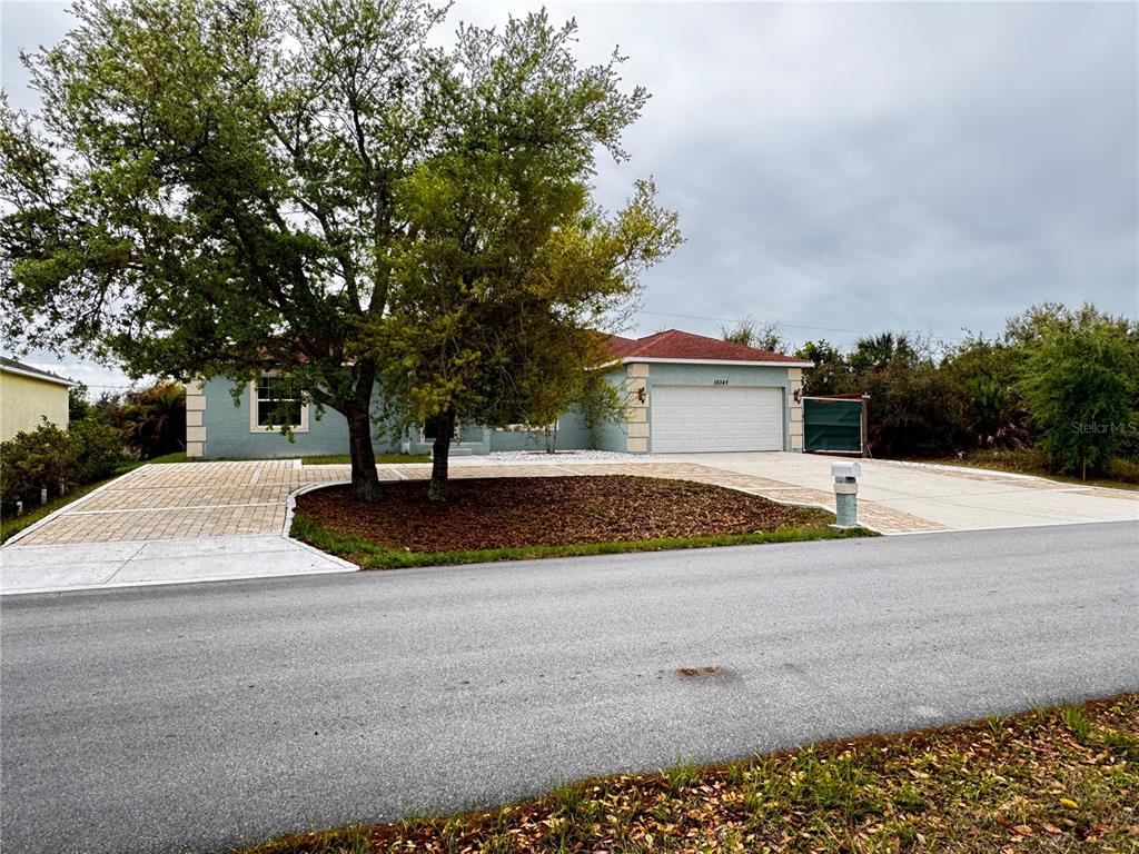 A single-story house with a paved driveway and a large tree in the front yard — 10347 GRAIL AVENUE, ENGLEWOOD, FL