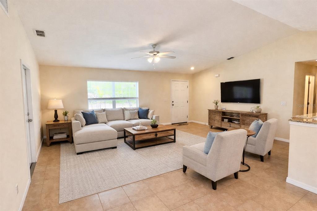 A living room features a sectional sofa, two armchairs, a coffee table, and a television — 10347 GRAIL AVENUE, ENGLEWOOD, FL