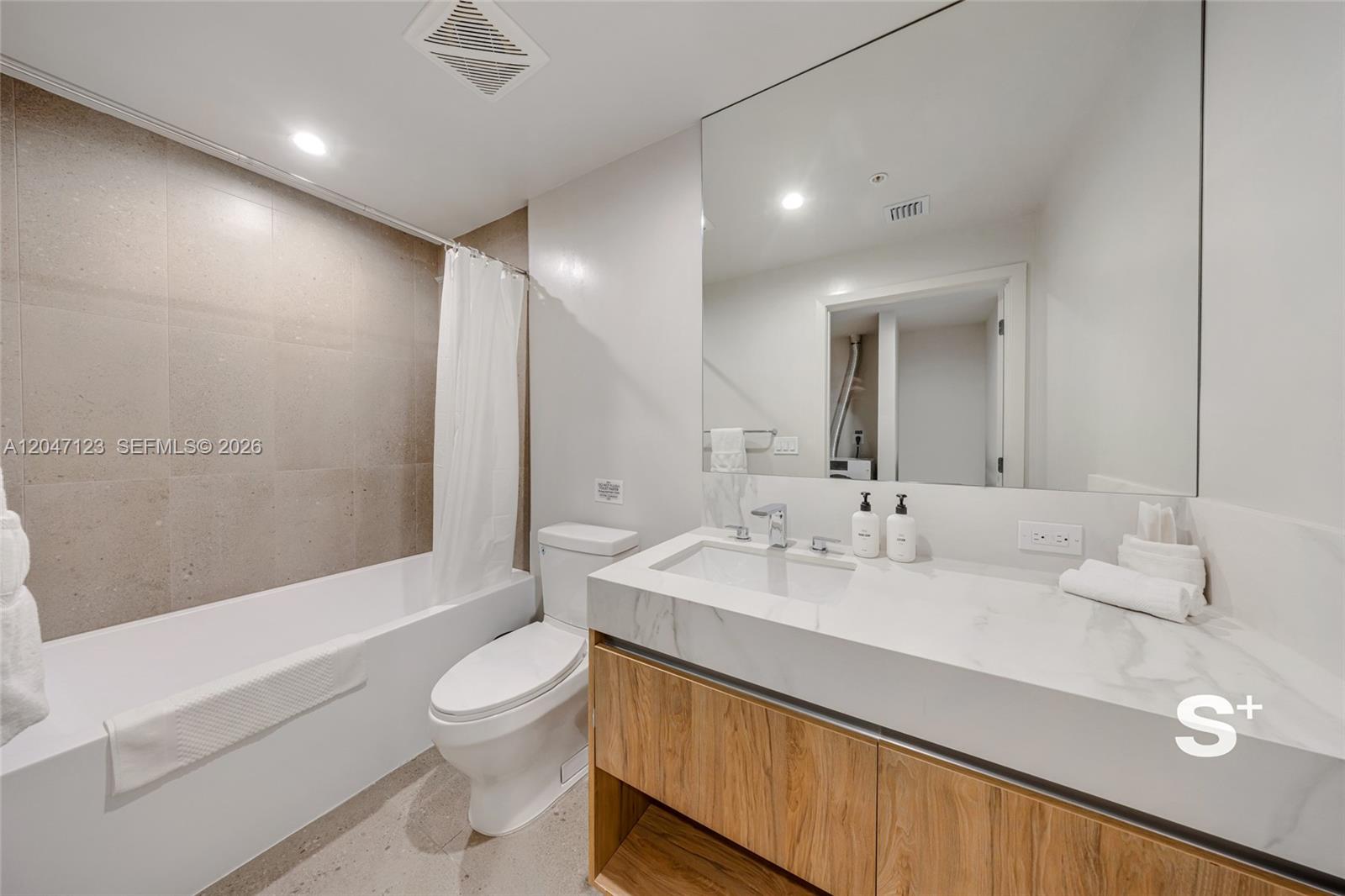 A modern bathroom features a white vanity with a marble countertop, toilet, and tiled bathtub — 11 NE 6th St # 2307, Miami FL 33132, MIAMI, FL