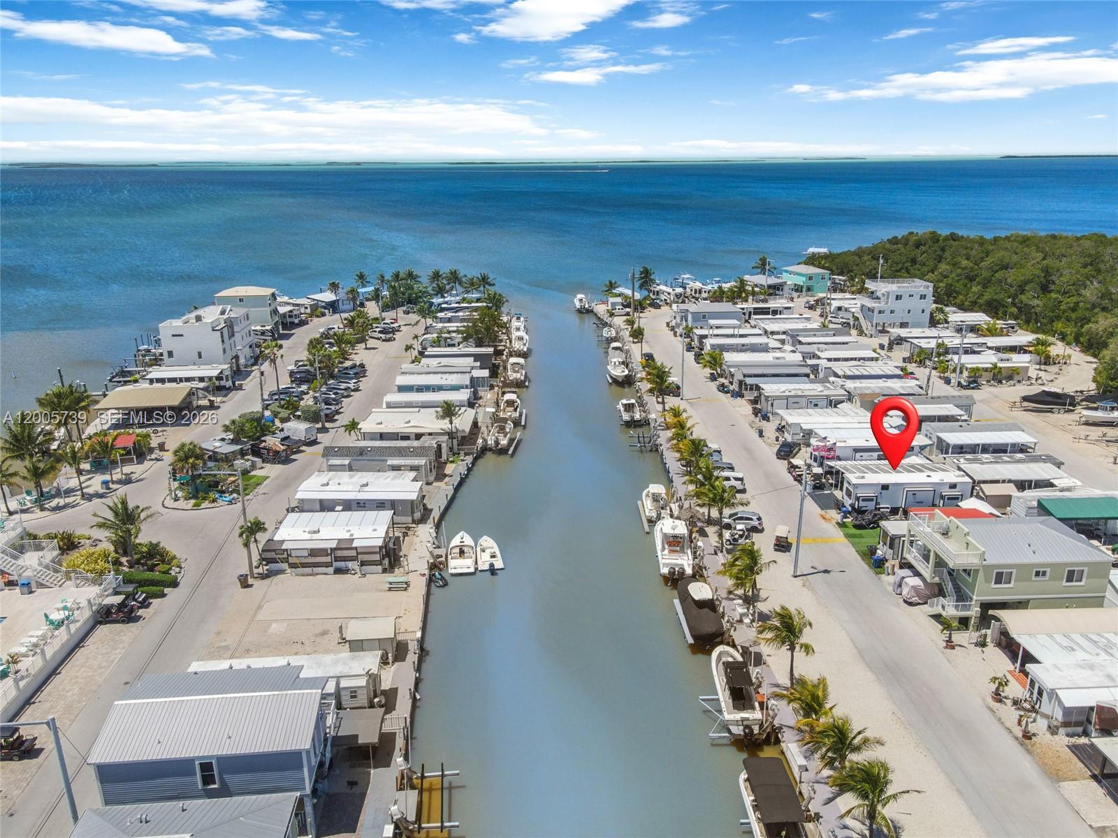 An aerial view shows a canal lined with mobile homes and boats near the ocean — 325 Calusa St #312, Key Largo FL 33037, KEY LARGO, FL