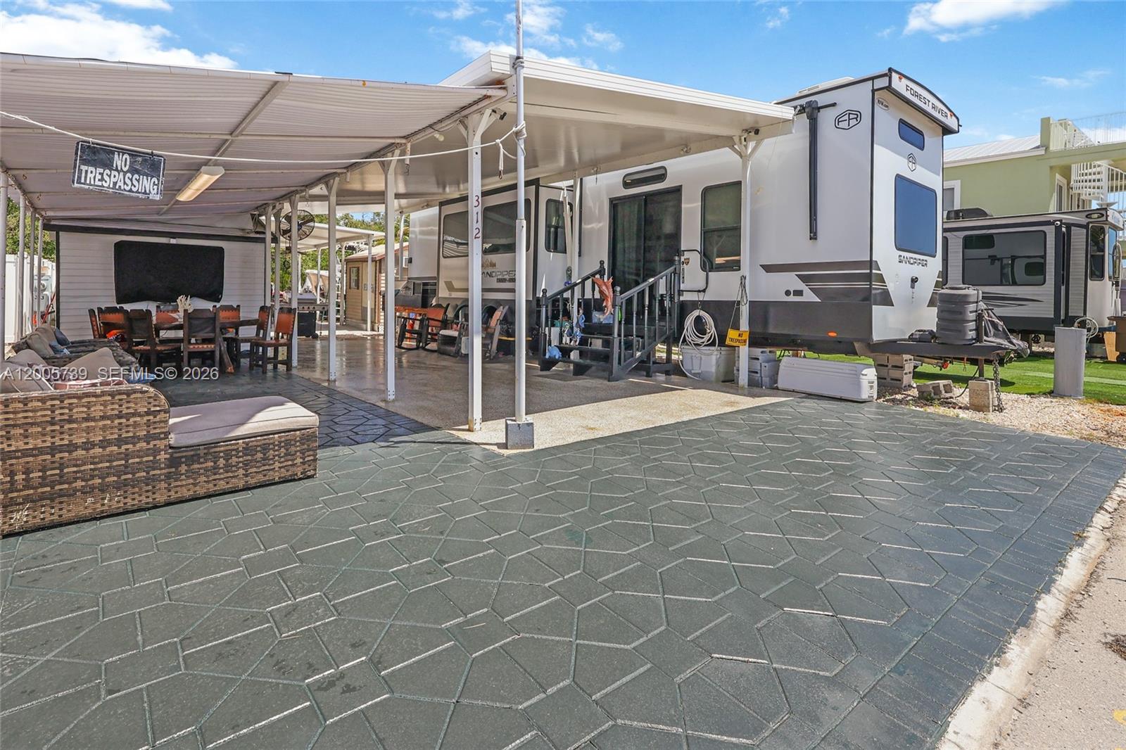 A large recreational vehicle is parked under a covered patio with a patterned concrete floor — 325 Calusa St #312, Key Largo FL 33037, KEY LARGO, FL