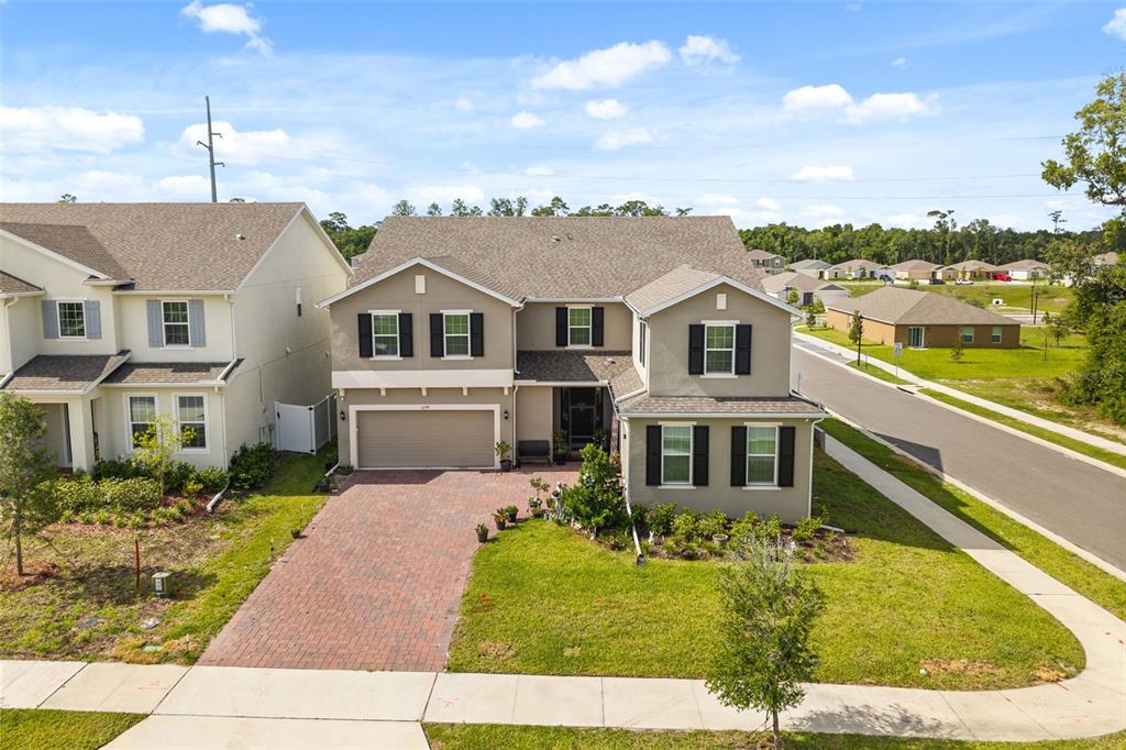 An aerial view shows a two-story suburban house with a brick driveway and attached garage — 1299 WOODLINE DR, DELAND, FL