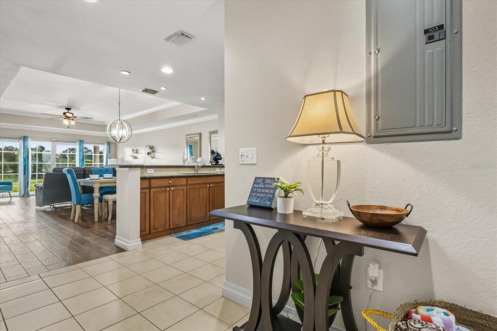 A foyer with a console table and lamp leads into an open-concept kitchen and dining area — 7604 CABANA COURT UNIT 103, REUNION, FL